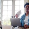 Woman fanning herself at home with laptop researching HRT help for anxiety and perimenopause mood changes
