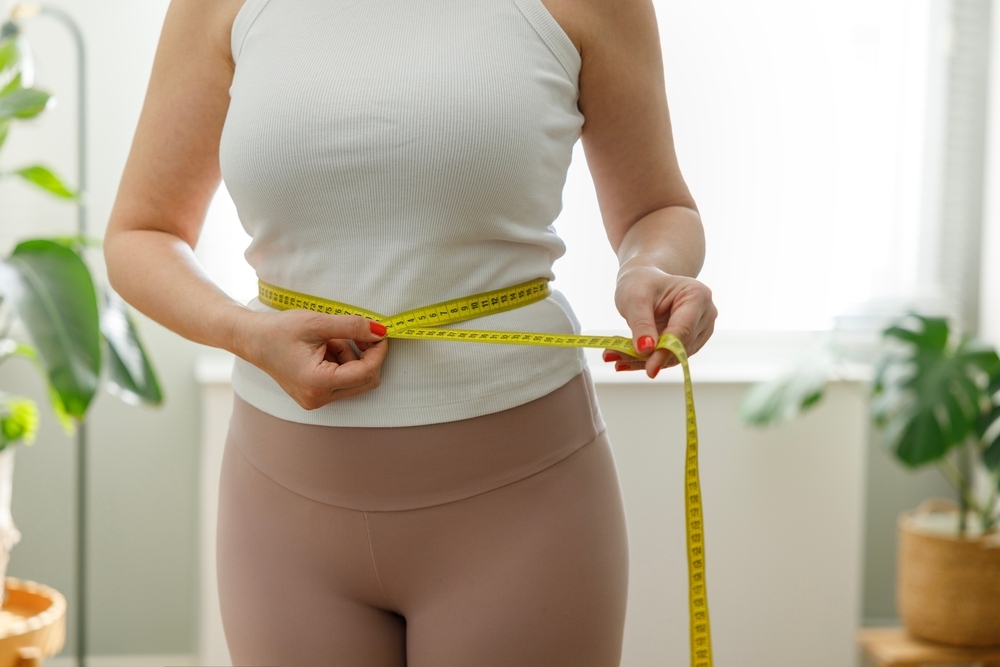Woman measuring waist tracking progress while on GLP-1 medications for medical weight loss