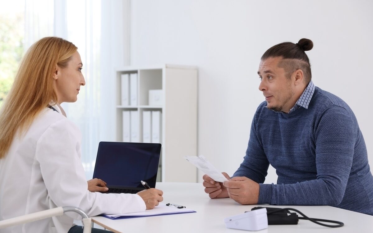 Doctor reviewing health records with a male patient during a medical weight loss candidate evaluation at a clinic