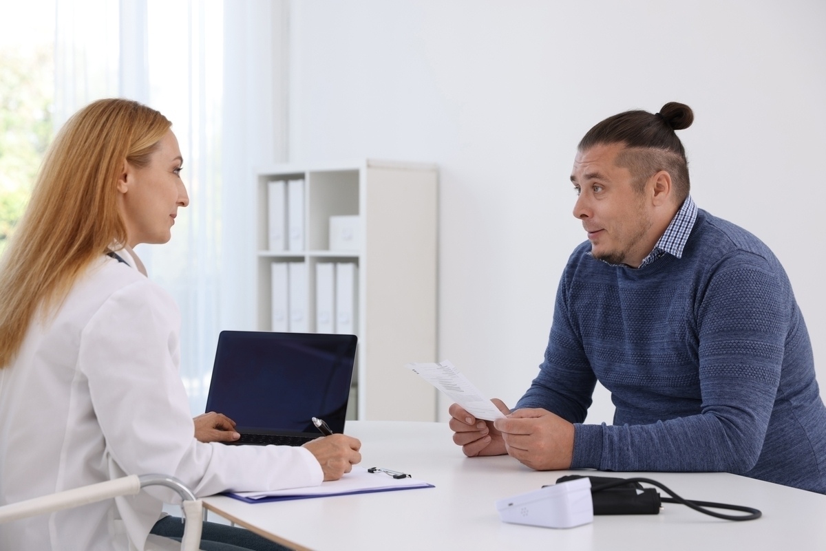 Doctor reviewing health records with a male patient during a medical weight loss candidate evaluation at a clinic