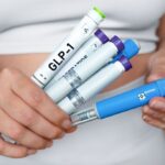 Person holding GLP-1 injection pens comparing semaglutide vs tirzepatide weight loss medication options side by side