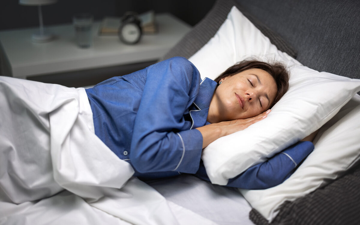 A woman in her 40s sleeping peacefully representing improved sleep quality through HRT for sleep in women during perimenopause and menopause
