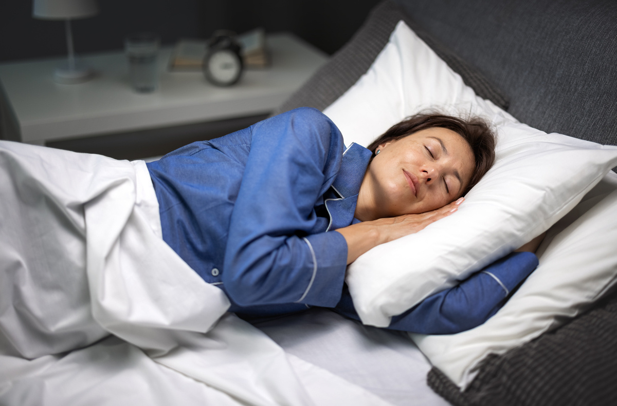 A woman in her 40s sleeping peacefully representing improved sleep quality through HRT for sleep in women during perimenopause and menopause