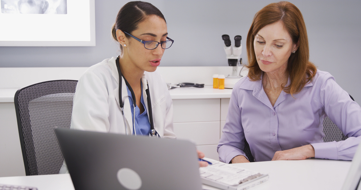 Female healthcare provider reviewing clinical information on a tablet with a female patient during a consultation about losing weight after 40